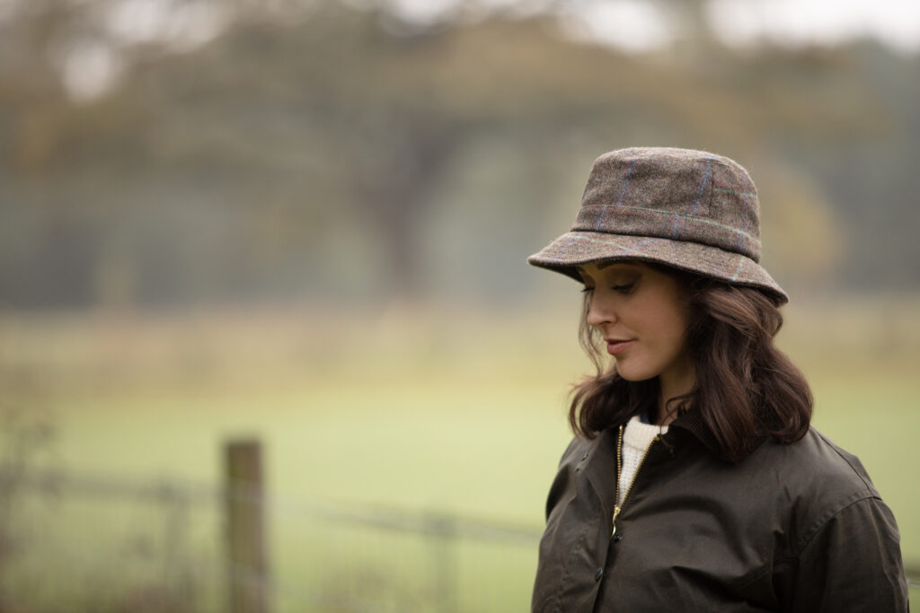 Woman in a waxed jacket wearing a tweed hat